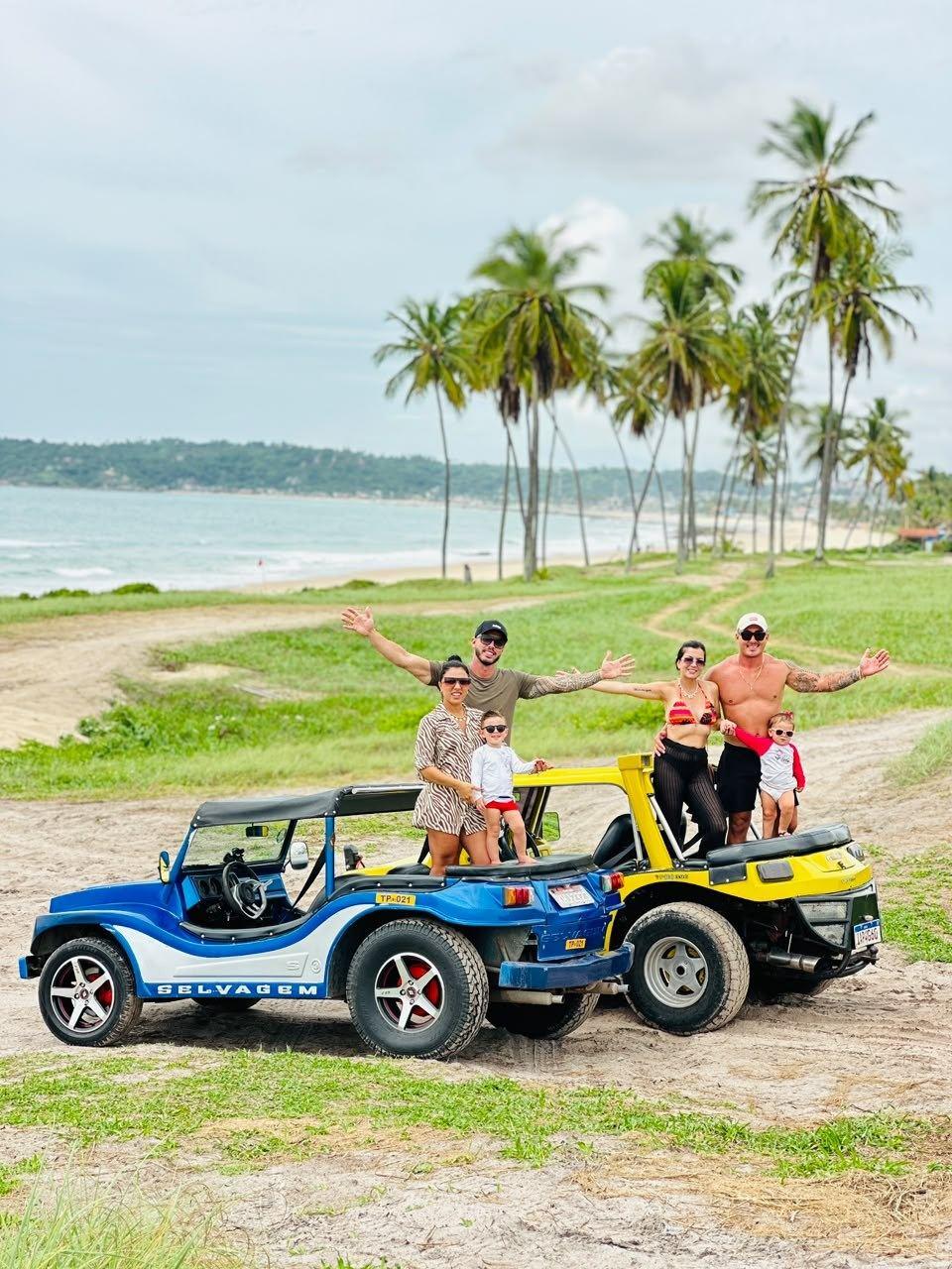 Família com crianças em dois buggys, um azul e um amarelo, à beira-mar em Porto de Galinhas