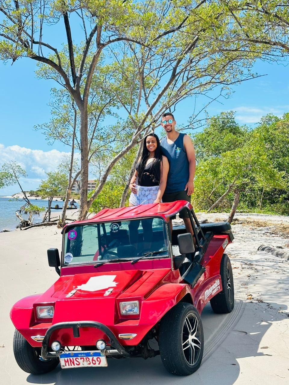 Casal no buggy vermelho Magnata Country em praia de areia branca com árvores
